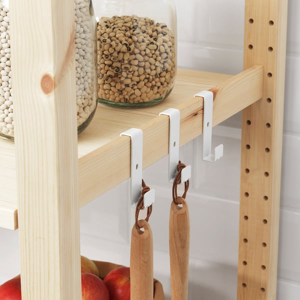 Wooden shelf with white hooks holding jars of pulses and wooden utensils.