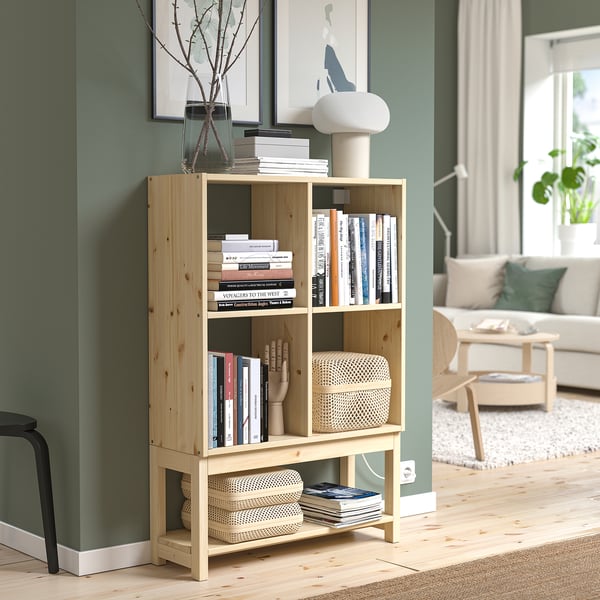 IVAR pine bookshelf against green wall, holding books, vases, and decor.