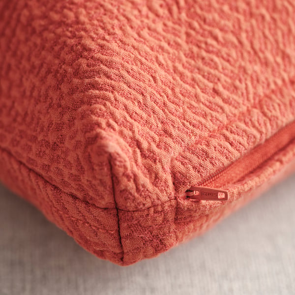 Close-up of reddish-orange JÄTTEGRAN cushion cover, showcasing its detailed leaf pattern and sturdy zip.