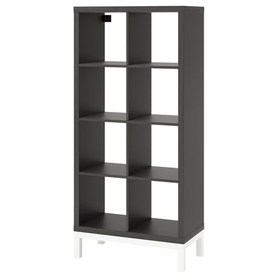 Black KALLAX shelving unit, minimalist design, rectangular shape, stands on white legs, made of particleboard & steel.