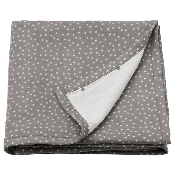 A folded grey muslin swaddle blanket with small white polka dots. Its soft, rectangular, and made from 100% cotton.