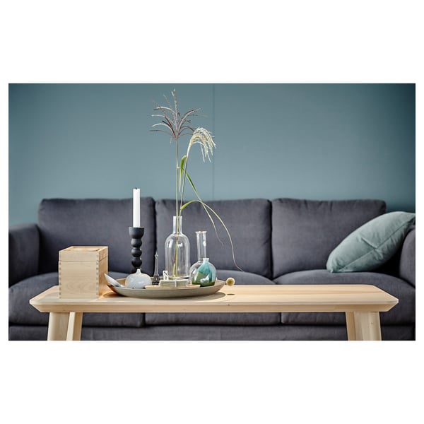 Modern living room with grey LISABO sofa, wood coffee table, decorative vases, and candle holder against blue wall.