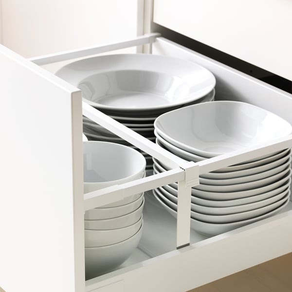 Open kitchen drawer with organised white plates and bowls, showcasing storage and accessibility.