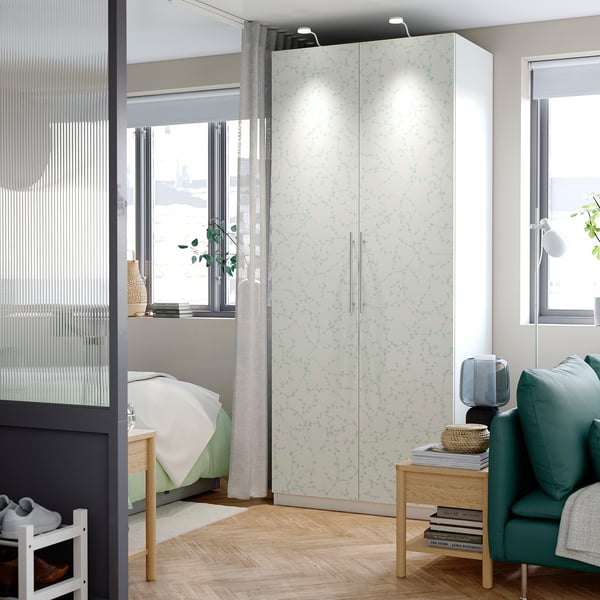 Modern bedroom with floral PAX wardrobe, window, chair, side table.