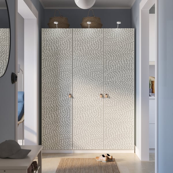 Modern bedroom with large grey PAX wardrobe, mirror, coat rack, and cabinet with decor.
