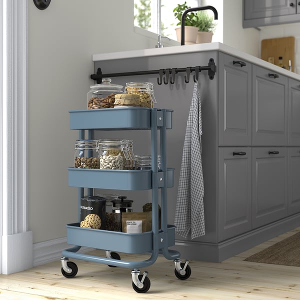 Blue ikea RÅSKOG trolley in kitchen, holding jars, fits under counter.