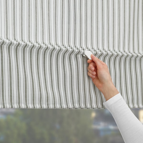 Person adjusting striped blind, demonstrating privacy control and light block feature.