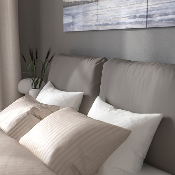 A modern upholstered bed with a sloped headboard and pillows, perfect for sitting and relaxing. The removable cover is machine washable.