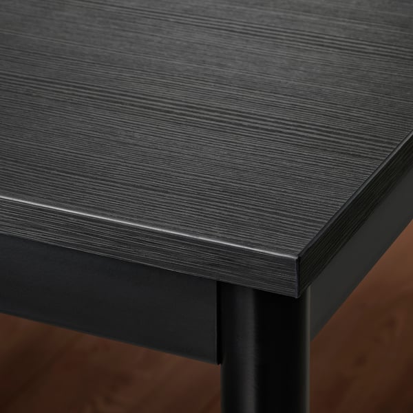 Close-up of sleek, dark-colored table with smooth, glossy top and sturdy metal edges.