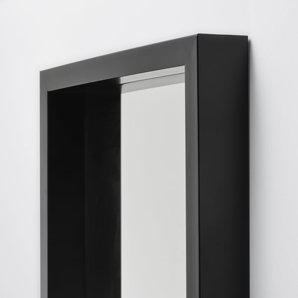 Black-framed floor mirror, reflecting light, modern and sturdy design, suitable for bathroom or living room.