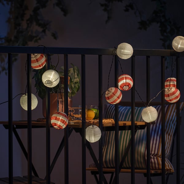 Balcony lit by solar-powered lanterns, creating atmospheric light. Lanterns hang from railing, providing decorative glow.