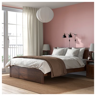 SONGESAND bed frame with pink walls, white & brown linens, tall wooden legs, two black lamps, small rug & bedside table.