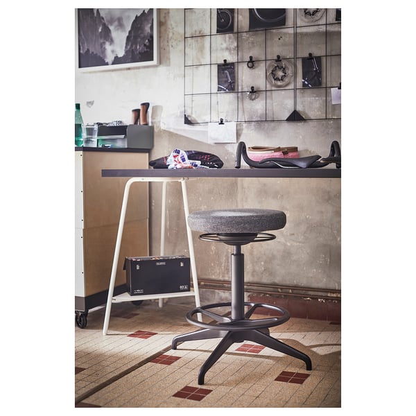 Modern home office setup with TILLSLAG adjustable stool and minimalist desk; sleek design, grey upholstery.