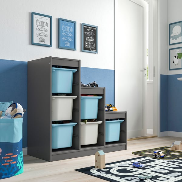 Kids room with TROFAST grey wooden storage, light blue bins, toy car prints, blue rug, toys.