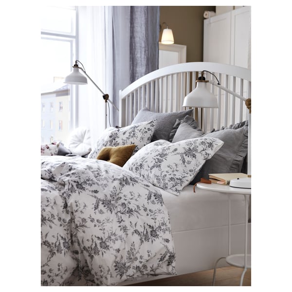 Cosy bedroom with white TYSSEDAL bed, floral linens, grey pillows, books, and wall lamps.