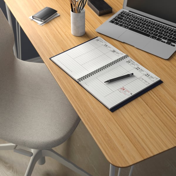 Wooden desk with grey chair, open notebook, pen, smartphone, and laptop. Organised workspace with modern style.