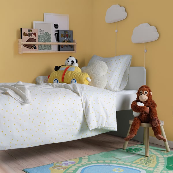 Kids room: yellow bed, stuffed animals, cloud decor, books.
