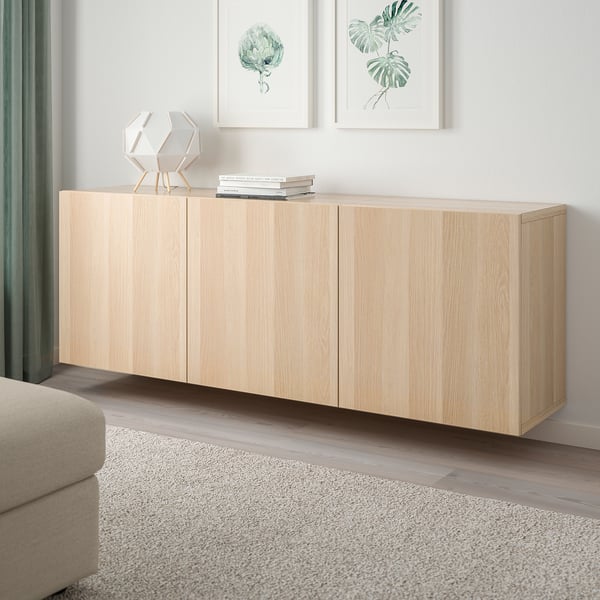 BESTÅ storage unit with doors in room, neutral wood, rug, sofa.