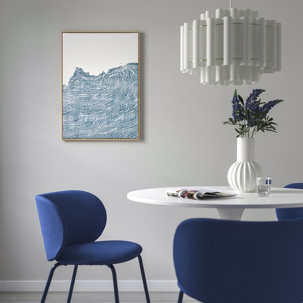 Living room with BLODFLÄDER art print over small table. Blue chairs, white vase with blue flowers.