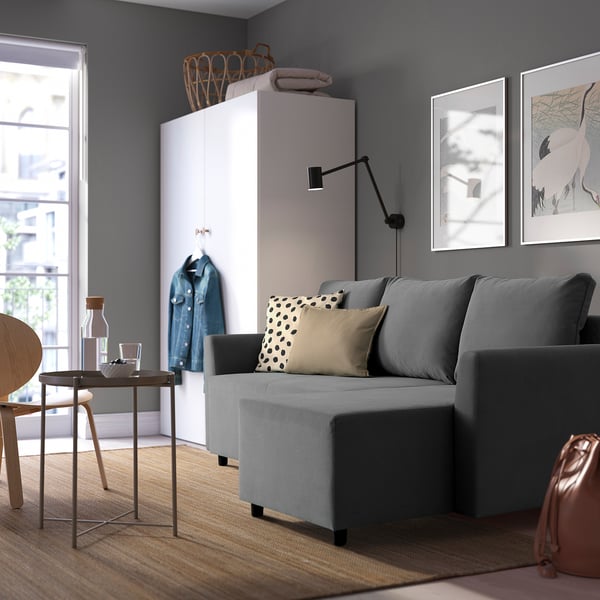 Modern living room with grey BRISSUND sofa-bed. Its large, fits well in space, beside a white cabinet and framed art.