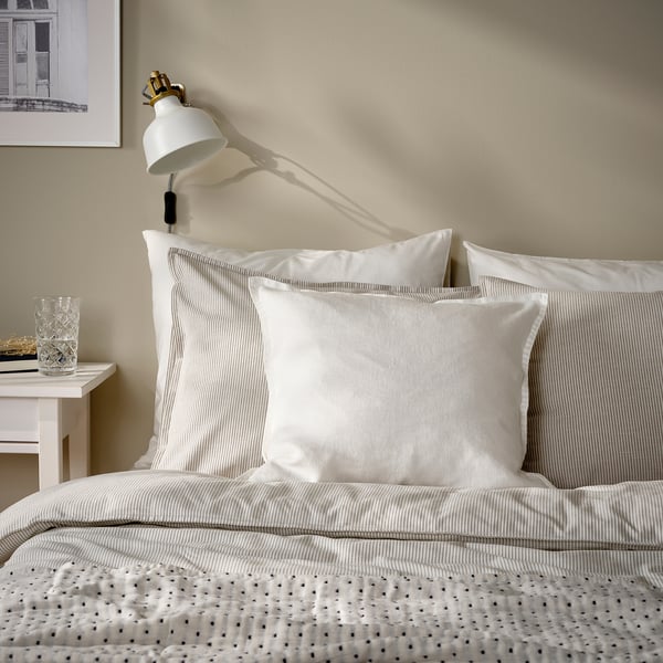 Bed with white DYTÅG pillows, wall lamp, simple cosy design.