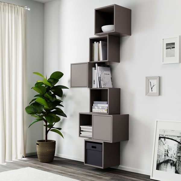 Modern living room with EKET bookshelf, books, decor, plant near window.