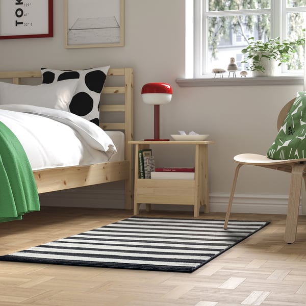 Stylish black & white rug in a well-lit bedroom, balancing decor with recycled polyester material.