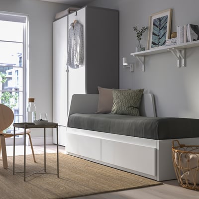 Convertible sofa-bed with storage drawers, cushions, shelves and table by window.
