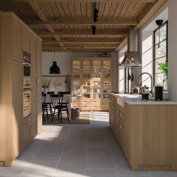 Modern wooden kitchen with light oak cabinets, black accents, and natural lighting.