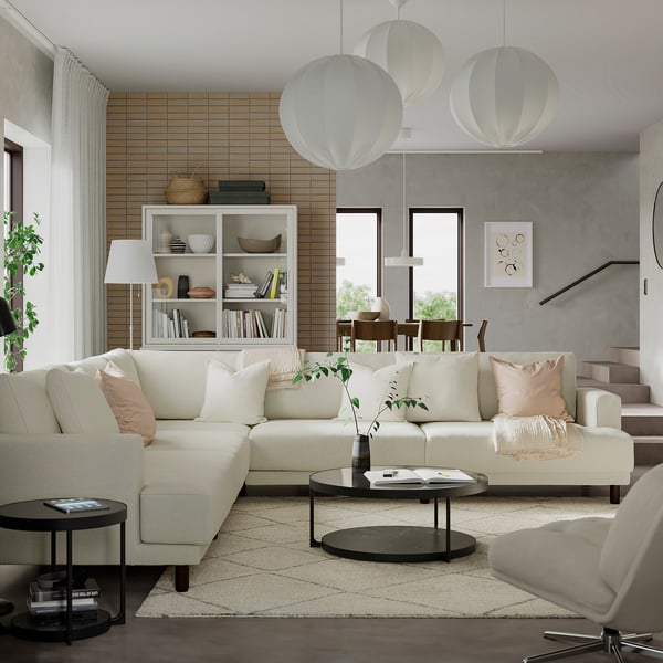 Modern living room with white l-shaped sofa, round black FRÖTORP coffee table, large windows, wooden shelves, and hanging white lanterns.