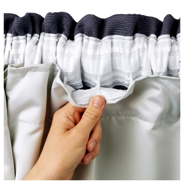Hand holding grey GLANSNÄVA curtains, showing inner material.