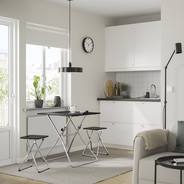 Modern kitchen with white cabinets, black metal table & stool, large window, compact for storage, stylish pendant light.