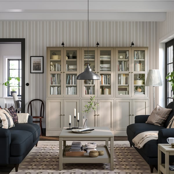 Modern living room with HAVSTA light pine bookcases, dark blue sofa, coffee table, patterned rug, and striped wallpaper.