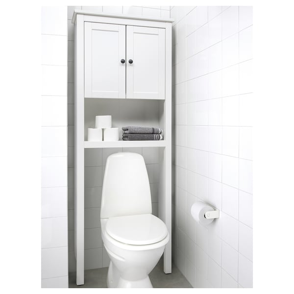 Clean, minimalist bathroom with HEMNES shelf unit above toilet storing towels and toiletries, with seamless white tiling.