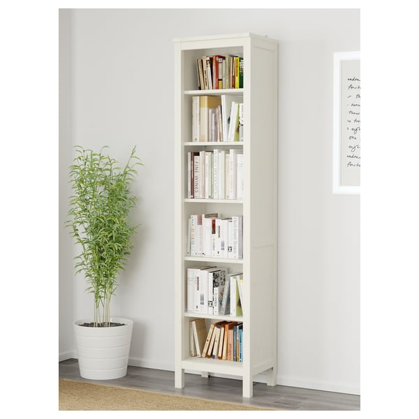 White wooden bookshelf with adjustable shelves, holding books and standing next to a potted plant.