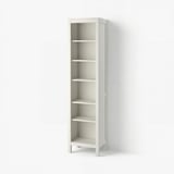 A tall, white HEMNES bookshelf. Made of solid pine, it has five adjustable shelves, standing on four legs. Its minimalist design suits various spaces.