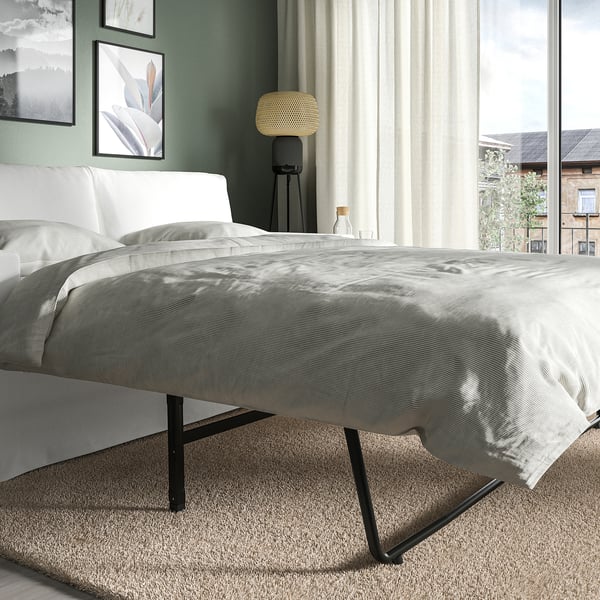 Modern bedroom with HYLTARP sofa-bed, featuring clean lines, soft comfort, and reversible cushions. Large window allows natural light.