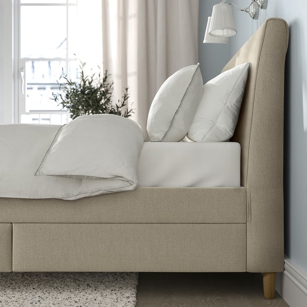 Upholstered bed with sloped headboard, drawers, and pillows.