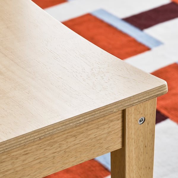 Light wooden table close-up. Smooth, polished surface, sturdy build, slight grain visible.
