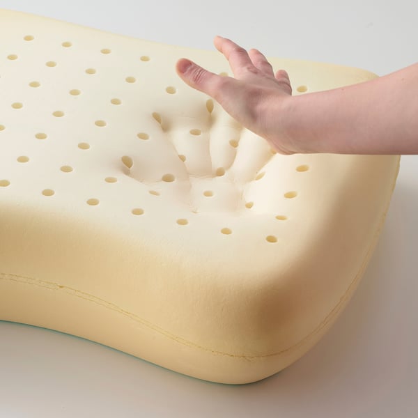 Image displays a hand pressing into a yellow pillow, showcasing its contouring memory foam.