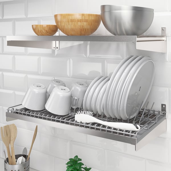 Metal dish rack on wall with cups, lids, plates, bowls, and cooking utensils; inspired by professional kitchens.