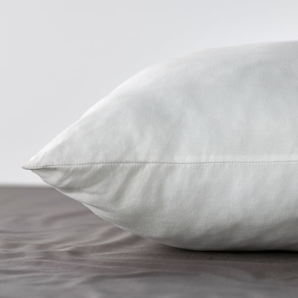 Close-up of a fluffy white pillow with smooth, textured fabric on a bed.