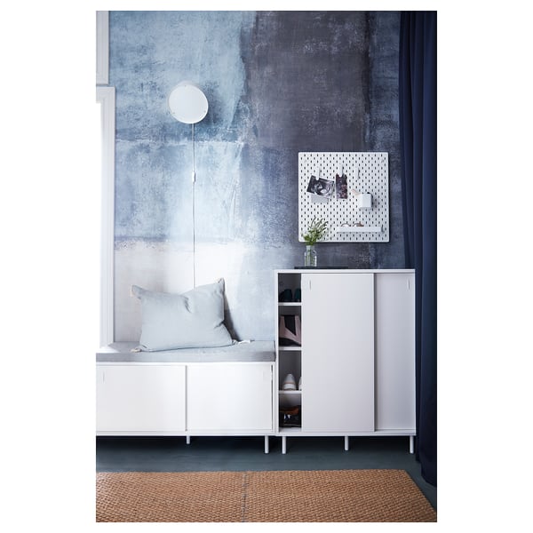 Modern, white MACKAPÄR shoe cabinet, sliding doors, grey wall, grey floor, hanging round light.