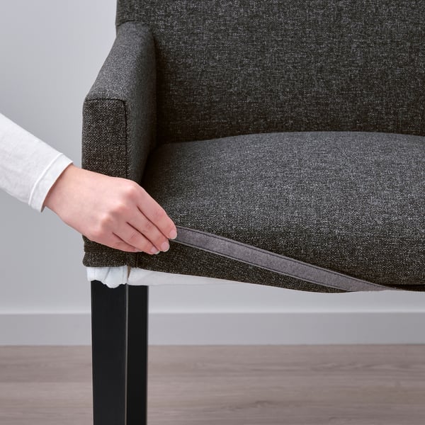 Person pulls off a grey chair cover, showcasing its removable feature.