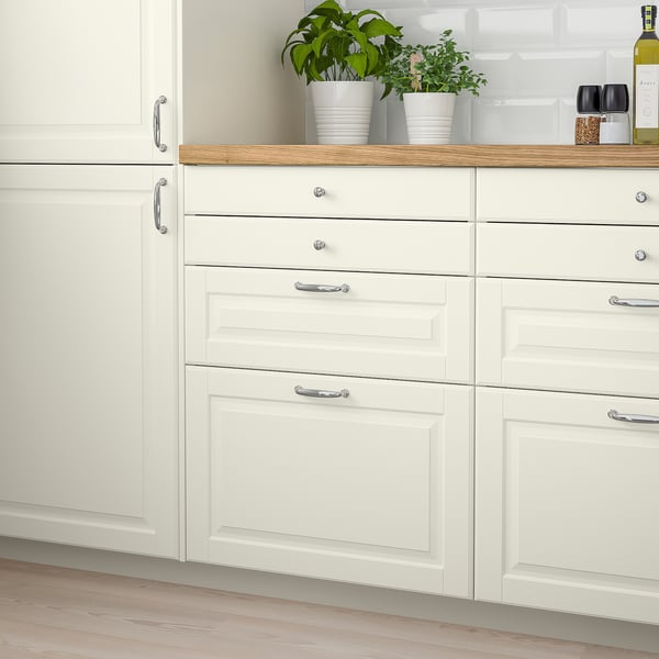 Modern kitchen with white MÖLLEKULLA wooden countertop, broad design, holding potted herbs and wine bottle.