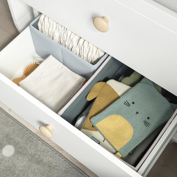 White dresser drawer open, showing folded colourful blankets, demonstrating storage functionality.