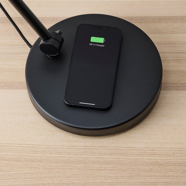 Black lamp wirelessly charges smartphone to 88%.