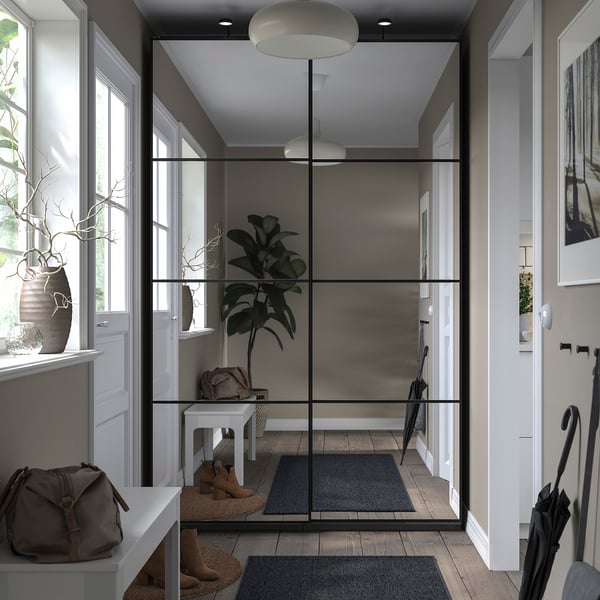 Modern entryway with glass-door closet, white decor, grey rug, plants, and umbrellas.