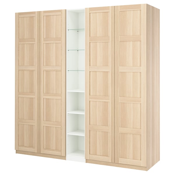 An IKEA PAX wardrobe in light oak finish. It four wooden doors with a panel design, hiding shelves inside.