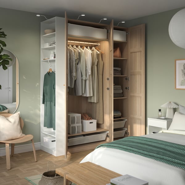 Modern bedroom featuring a PAX wardrobe with hangers, shelves, and organised storage. It efficient space utilisation with clothes hanging and folded.